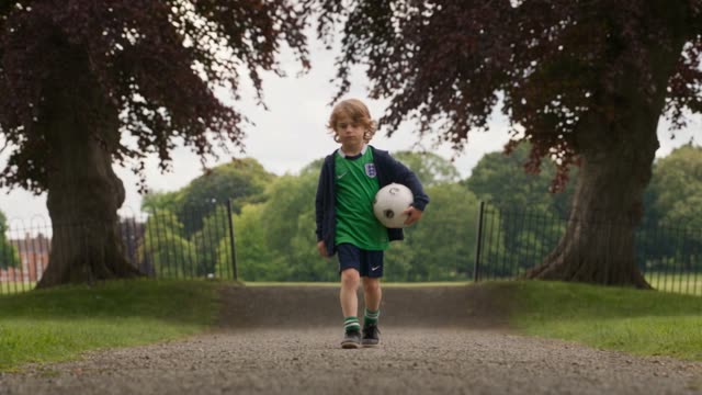 The movie playing at minute 24: a boy with a football in a city park